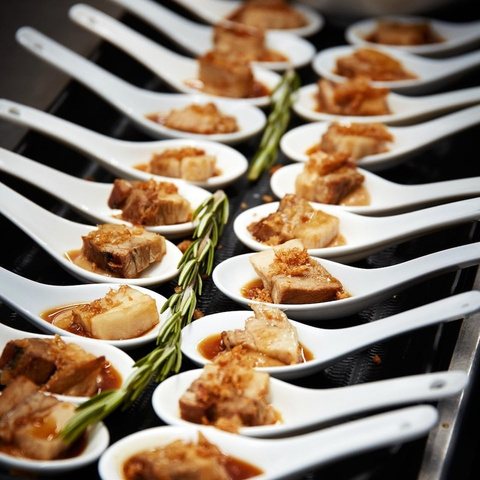 A long line of identical canapés plated on white spoons.